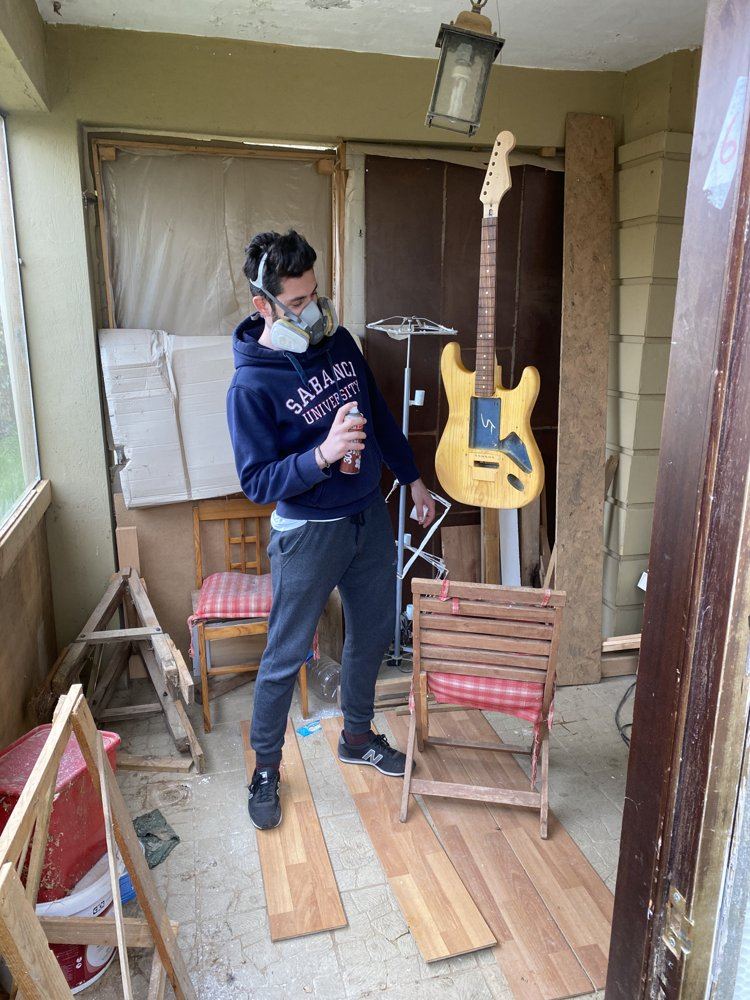 Spray painting a guitar body in a respirator